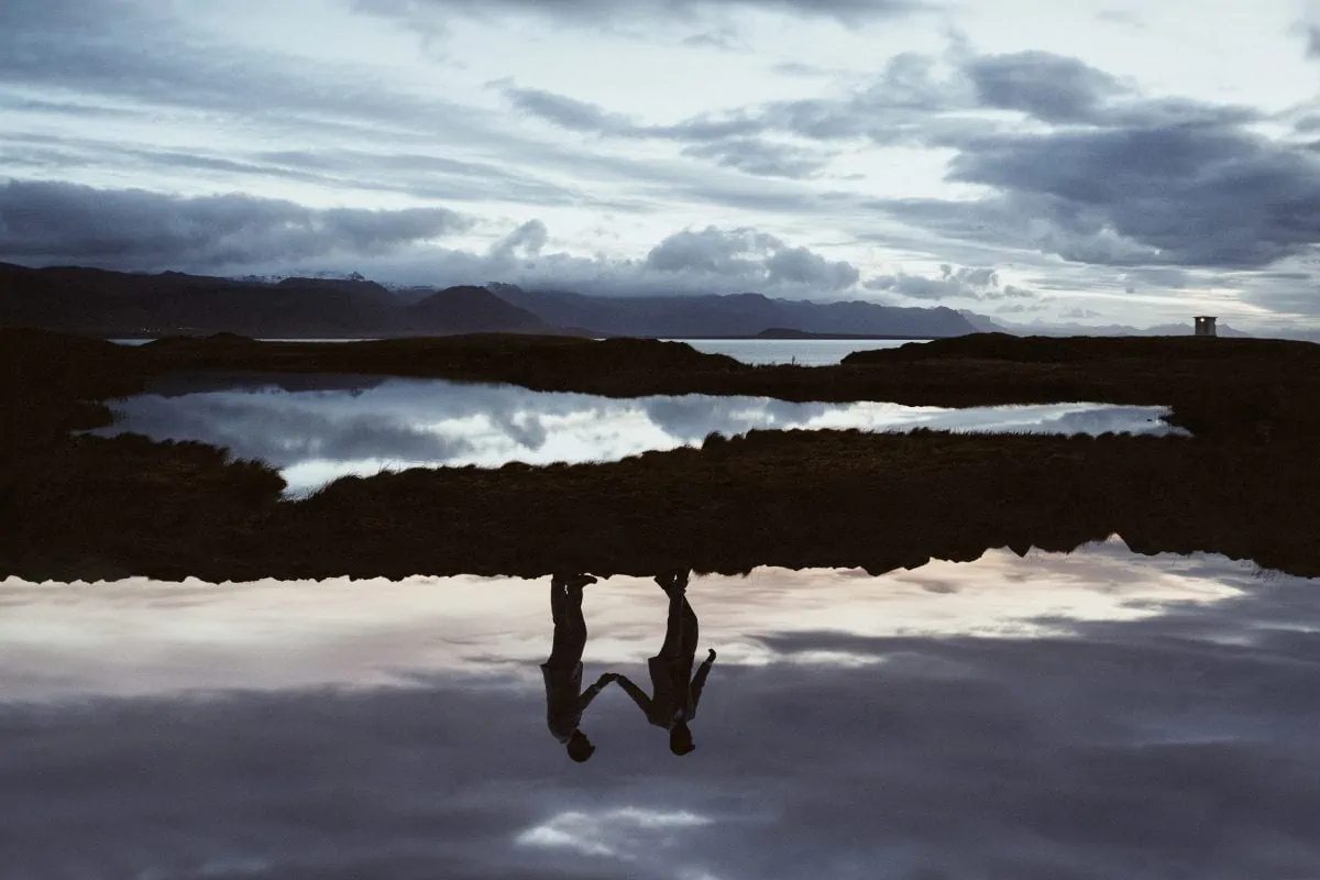 An artistic image showing the reflection of a gay couple during sunrise in Iceland on their elopement wedding day. 